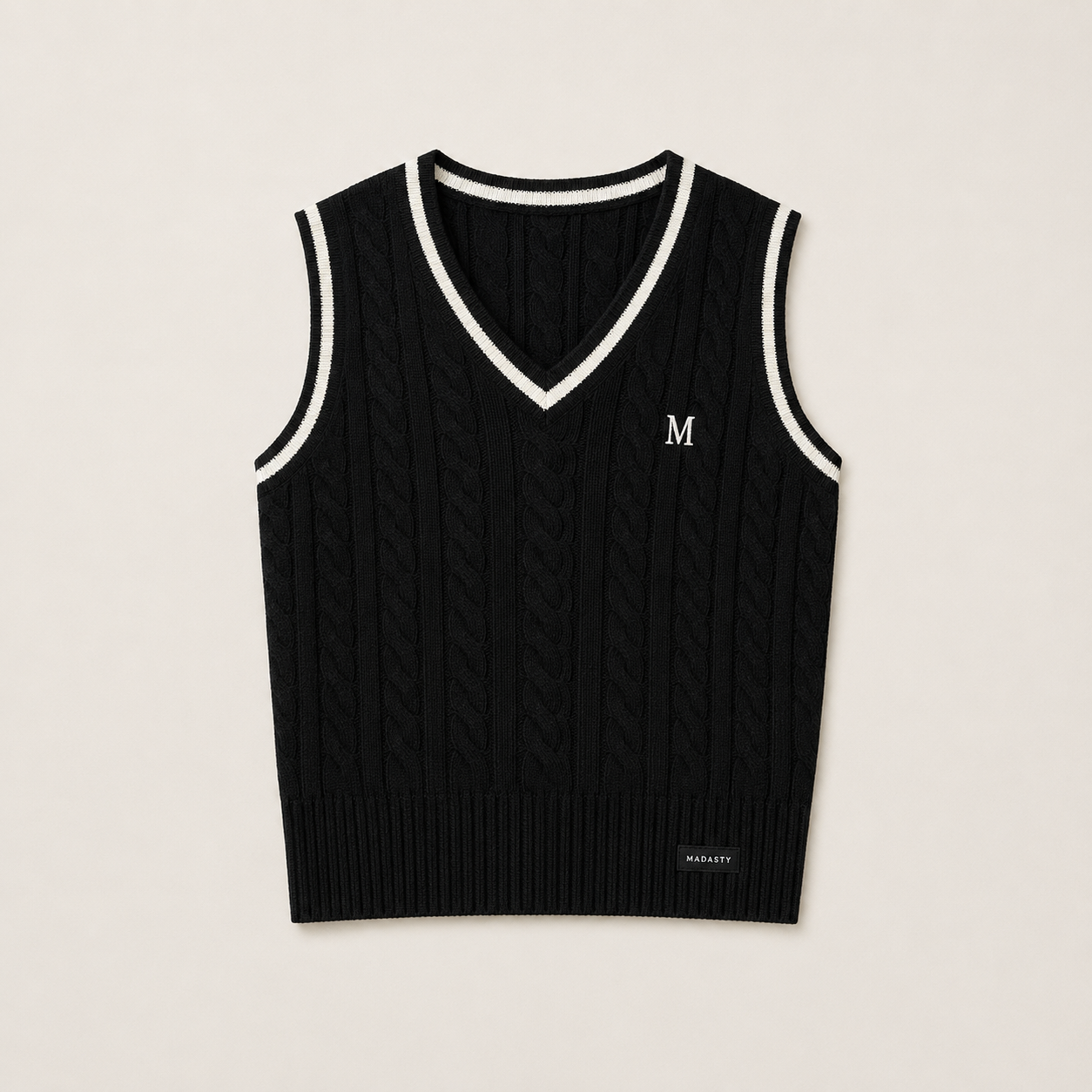 Madasty Signature Cable-Knit Vest

A timeless layering piece designed for polished, effortless style. This black cable-knit vest features crisp cream trim along the V-neck and armholes, a delicate embroidered M on the chest, and a subtle Madasty label at